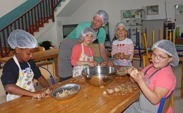 Un groupe d'enfants et leur animateur épluchent des pommes de terre