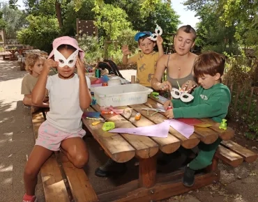 une groupe d'enfants et leur animatrice montrent des masques de carnaval