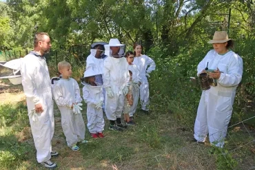 Un groupe habillé en apiculteurs observent un enfumoir