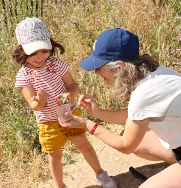 une maman et sa fille observent le contenu d'une boîte loupe