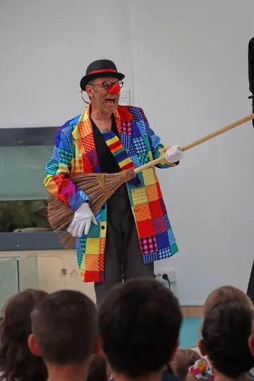 un clown joue avec un balai