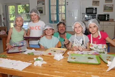 une groupe d'enfants et leur animateur sont en cuisine avec des sucettes