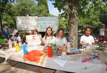 Un groupe d'enfants et leurs animateur peignent sur des tissus