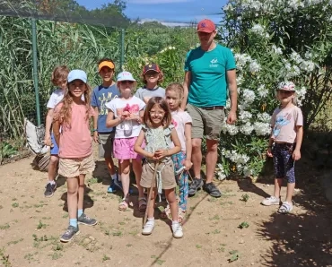 une groupe d'enfants et leur animateur sont dans un enclos avec un dindon