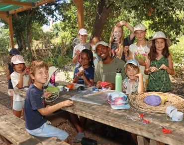 Un groupe d'enfants et leur animateur montrent du jonc et de la laine