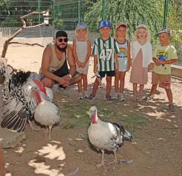 Un groupe d'enfants et leur animateur posent derrière des dindes et un dindon