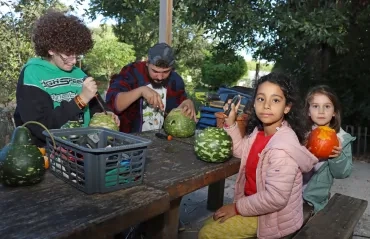 Deux enfants et leurs animateurs creusent de courges