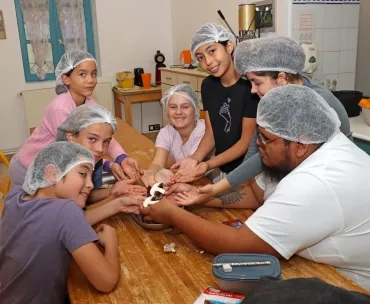 Un groupe d'enfants et leur animateur sont en cuisine et tiennent des morceaux de champignons