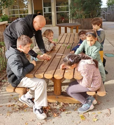 Un groupe d'enfants et leur animateur frottent avec des limes des noyaux