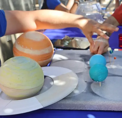 Mains d'enfants autour de maquettes de planètes