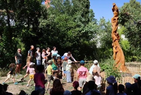 un groupe d'enfant et d'adulltes sont prêts d'une statue en bois