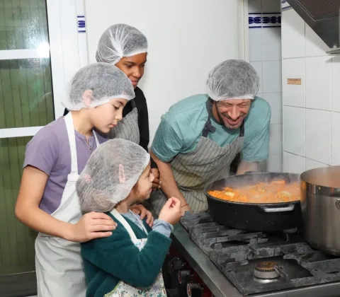 Un groupe d'enfants et leur animateur sont en cuisine autour d'une grosse marmite de soupe