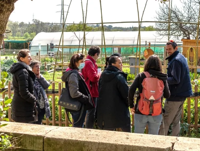 Un agent et un groupe d'adulte observent le jardin des possibles de l'Écolothèque