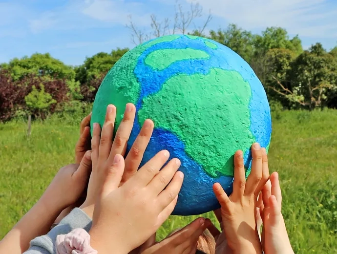 des mains d'enfants tiennent une planète Terre en papier maché