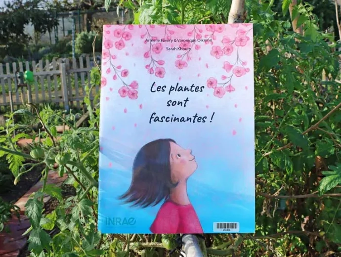 Le livre Les plantes sont fascinantes est présenté au milieux de différents plantes pour illustrer son contenu