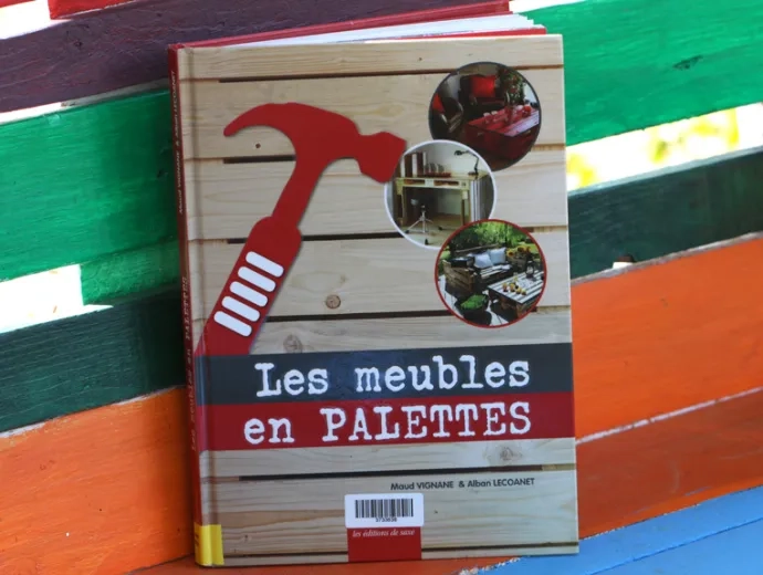 Le livre Les meubles en palettes est exposé sur un banc réalisé en palettes et peint avec de vives couleurs