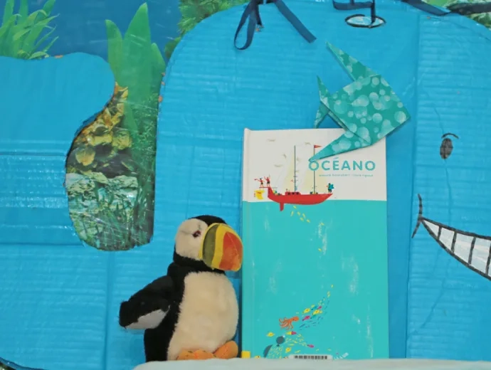 Le livre Oceano est exposé entouré d'une baleine bleue en carton et d'une peluche de macareux
