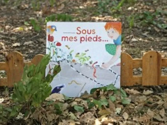 Le livre Sous mes pieds est exposé au sol, dans un sous bois entouré de feuilles mortes