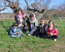 Un groupe d'enfants et leur animatrice cueillent de l'herbe