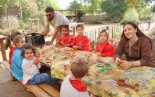 un groupe d'enfants et leur animateur sont assis autour d'une table avec de l'argile