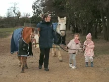 deux d'enfants et leur animatrice guident deux chevaux