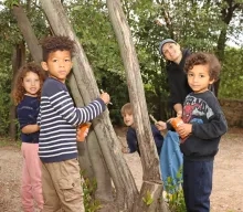 Un groupe d'enfants et leur animatrice peignent des troncs d'arbre