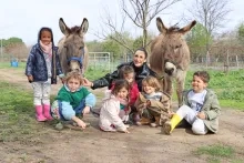 Un groupe d'enfants et leur animatrice posent avec deux ânes