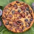 Un clafoutis est posé sur des feuilles de figuier, entouré de figues