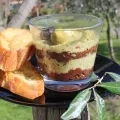 Une verrine de tapenade avec des couches noires et vertes avec deux tranches de pain grillées