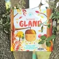 Le livre Le petit gland est exposé face 1ere de couverture, au creux d'un tronc d'arbre