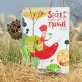 Le livre Le secret le plus fort du monde est exposé première de couverture, sur l'herbe jaunie. Un abri à abeille sauvages est posé contre le livre.