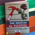 Le livre Les meubles en palettes est exposé sur un banc réalisé en palettes et peint avec de vives couleurs