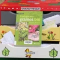 Le livre produire ses graines bio est exposé sur le tiroir ouvert d'une grainothèque