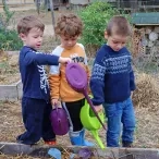 3 enfants dans un jardin avec des arrosoirs