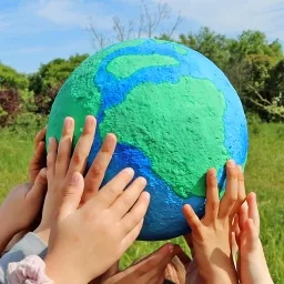 des mains d'enfants tiennent une planète entre les mains