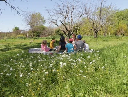 Un groupe d'enfant avec leur animatrice dans un espace enherbé et fleuri