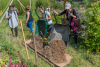 dans un jardin, des participantes déposent, avec des brouettes, une couche de terre pour élaborer une butte