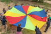 Un groupe d'adultes tient une toile multicolore de parachute pour orienter une balle
