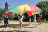 des enfants jouent en tenant chacun un bout d'une toile de parachute : un jeu cooperatif