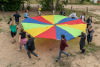 un groupe d'adultes fait tourner une toile colorée de parachute