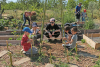 une animatrice et un groupe d'enfant construisent un tipi au jardin pour faire grimper des volubilis