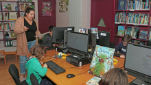 Des enfants et une animatrice font des recherches sur les ordinateurs de la médiathèque de l'Écolothèque 