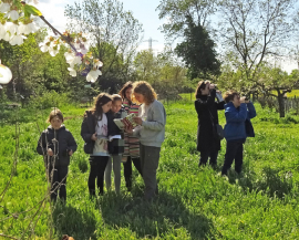 Un groupe d'enfants avec des parents et un animateur observent à la jumelle et identifient à l'aide d'un livre des oiseaux sauvages à l'Écolothèque