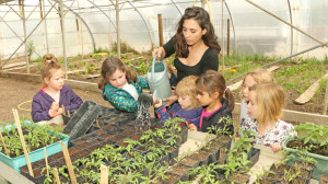 6 enfants et leur animatrice arrosent des semis dans la serre