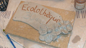 Une plaque d'argile décorée de fleurs avec l'inscription « Ecolothèque »