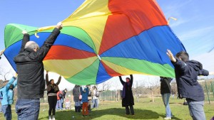 Des adultes et des enfants coopèrent en jouant au jeu du parachute