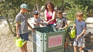un groupe d'enfants et leur animatrice entretiennent le composteur de jardin