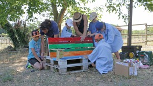 Deux adultes et cinq enfants construisent un banc en palettes