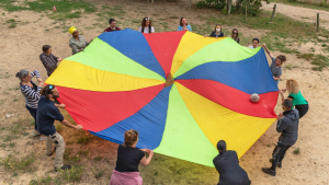 Un groupe d'adultes tient une toile multicolore de parachute pour orienter une balle