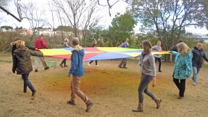 Un groupe d'adultes tournent en tenant une toile de parachute colorée